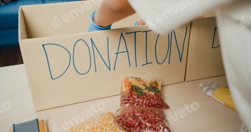 Preview: Girl volunteer wear gloves packing food and drinks donation into donations paper boxes.