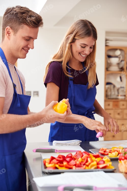 Preview: Male And Female Adult Students Preparing Ingredients For Dish In Kitchen Cookery Class