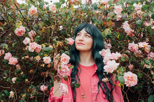 Preview: Portrait of smiling romantic hipster woman with green hair in pink magenta dress on blooming roses