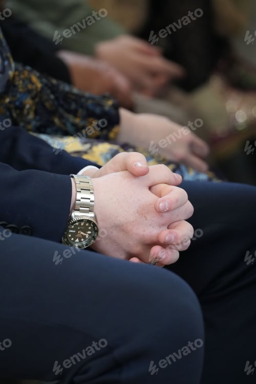 Preview: Closeup of a businessman in formal attire sitting hands clasped