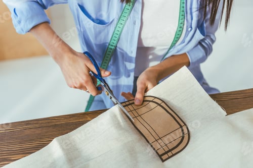 Preview: cropped image of seamstress cutting fabric with scissors