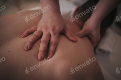 Preview: Young male enjoying relaxing body massage done by professional masseur in spa salon