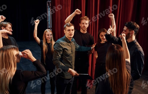 Preview: Practice in progress. Group of actors in dark colored clothes on rehearsal in the theater