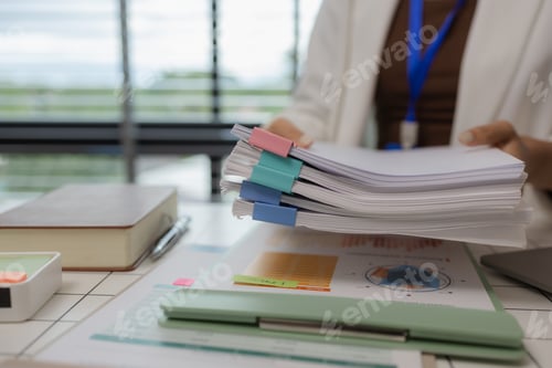 Preview: there are a lot if documents pied up on the desk if the data analysis team leader