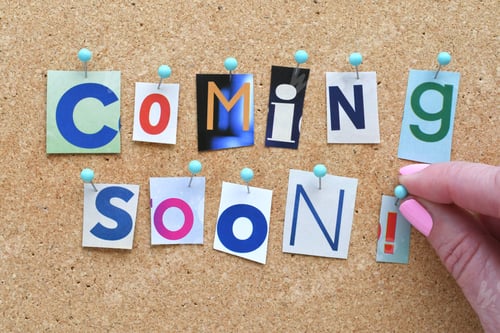 Preview: Person pinning a Coming Soon notice to a cork bulletin board.