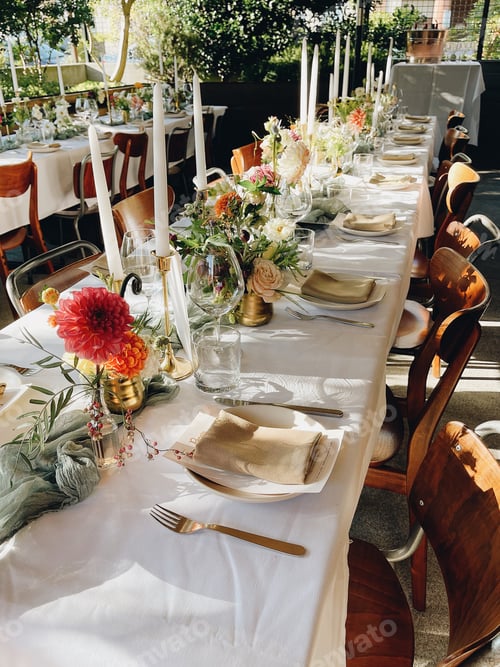 Preview: Beautiful long wedding reception table with wood chairs & adorned with wildflowers & white candles