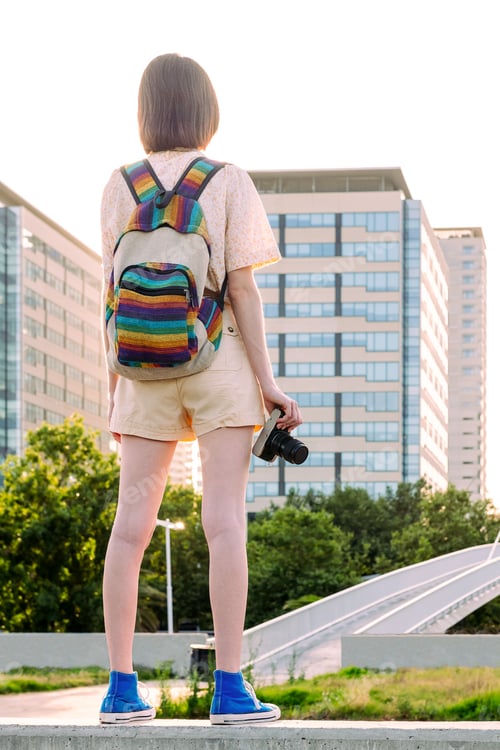 Preview: young woman with backpack and camera at the city