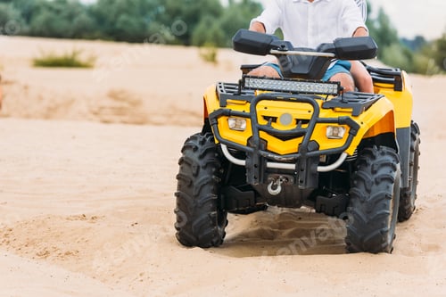 Preview: cropped shot of couple riding all-terrain vehicle on sand