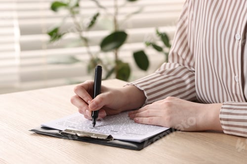 Preview: Woman Reviews Document on Clip Board with Pen