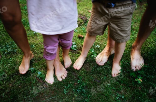 Preview: Bare feet of family with small children standing barefoot outdoors in nature, grounding concept