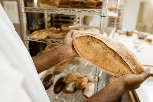 Preview: cropped shof baker holding fresh loaf of bread on baking manufacture