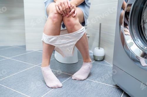 Preview: Woman sitting on toilet, experiencing urinary or digestive discomfort