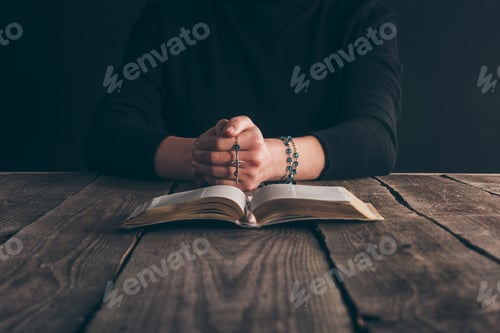 Preview: cropped image of woman sitting at table with rosary and bible and praying