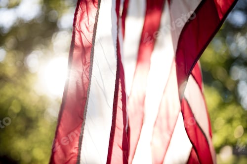 Preview: Closeup shot of the unites states flag hanging with the sun shining in the background