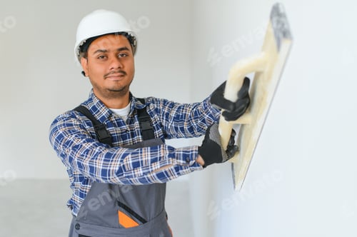 Preview: An Indian worker works in an empty apartment. A man in a uniform makes repairs inside the building