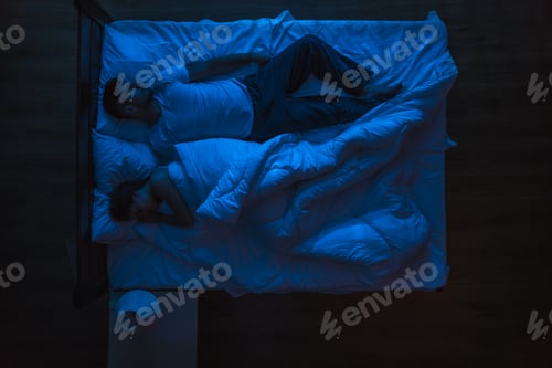 Preview: The man and woman sleeping on a bed. Evening night time. View from above.