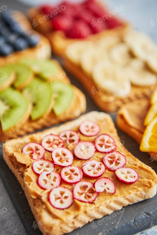 Preview: Six toasts with peanut butter, fresh fruits on a grey slate