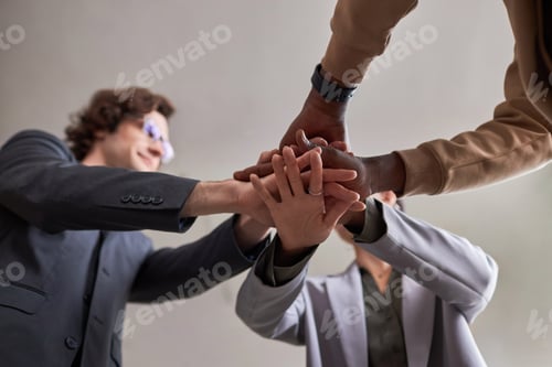 Preview: Diverse business team joining hands in unity celebrating success