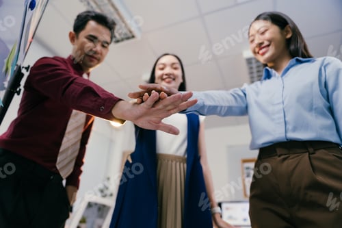 Preview: Smiling businesspeople joining hands together, showing unity and cooperation in achieving a common g