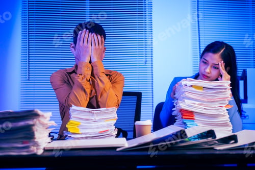 Preview: A businessman and woman are working overtime at their desks office at night.They are busy,stressed