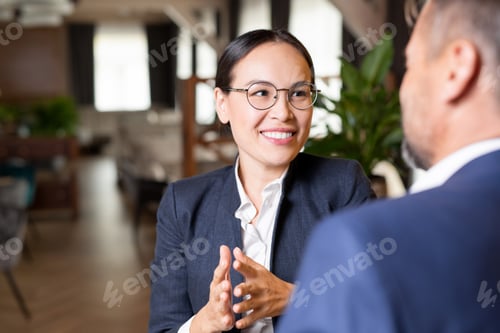 Preview: Young successful businesswoman with toothy smile talking to her business partner