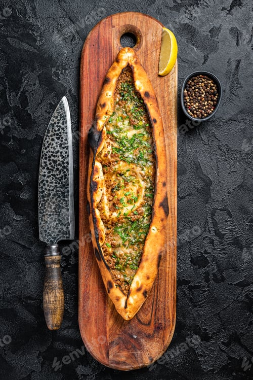 Preview: Turkish pide pie with beef meat and vegetables. Black background. Top view