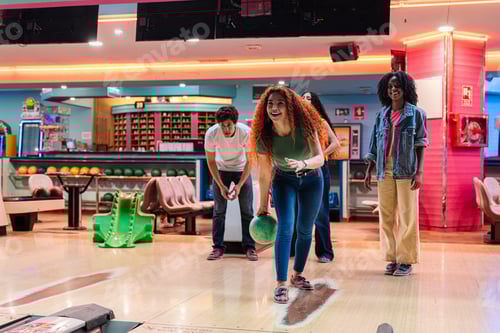 Preview: Young woman bowling with friends in a bowling alley