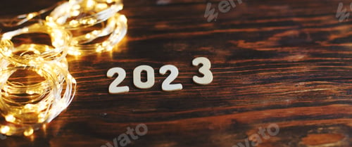 Preview: wooden number 2023 on christmas shiny wooden background. with sparkle festive gold garland