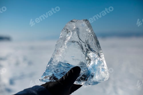 Preview: man wearing winter blue jacket and holding piece of transparent crushed ice cube