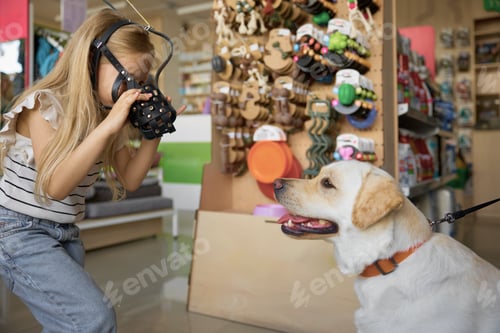 Preview: Cute little girl showing muzzle for dog at pet shop