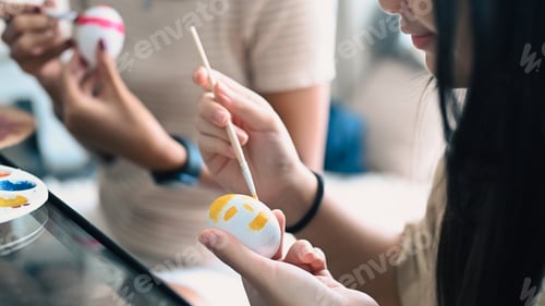 Preview: Smiling child hand painting Easter eggs at home. Easter, holidays and people concept.