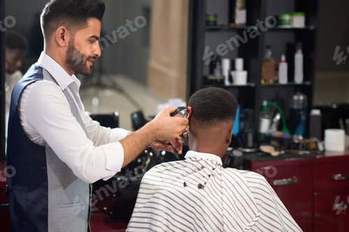 Preview: Barber trimming hair of male with clipper in barber shop