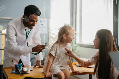 Preview: Smiling pediatrician with stethoscope checking little girl's lungs