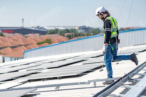 Preview: Male engineer installing or checking the working condition of solar panels on the roof