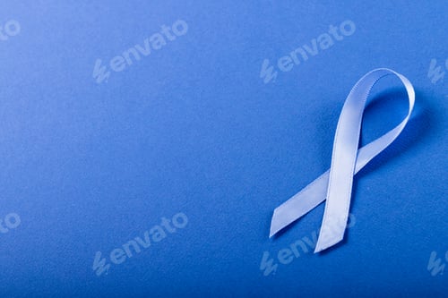 Preview: High angle view of blue stomach cancer awareness ribbon isolated against blue background, copy space