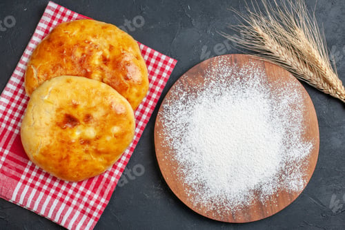 Preview: Above view of delicous fresh baked pastries on red stripped towel and flour on the wooden cutting