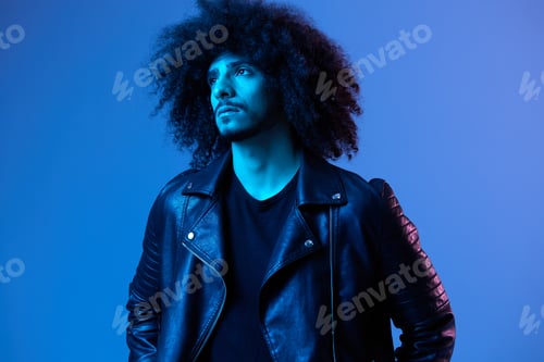 Preview: Portrait of fashion man with curly hair on blue background multinational, colored light, black