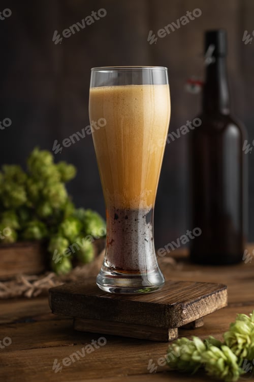 Preview: Beer. High foam in a glass after pouring beer. A glass of beer with hops on a vintage wooden board.