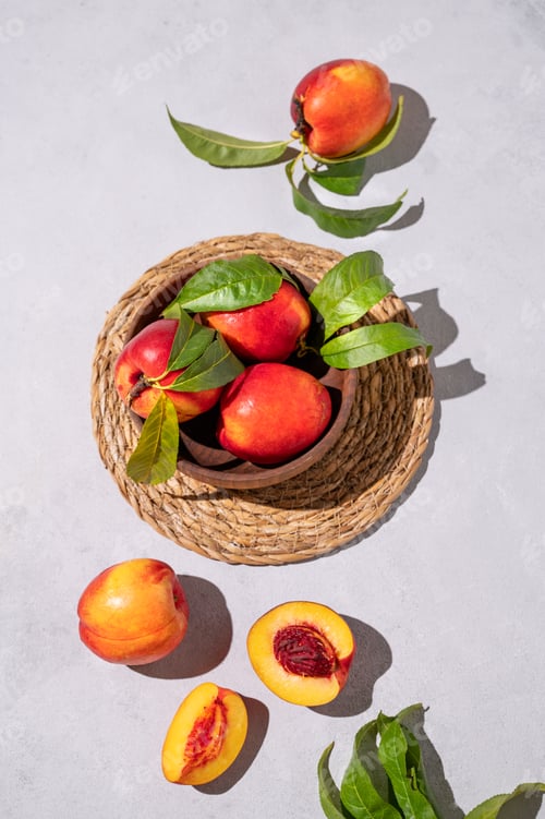 Preview: Juicy and sweet nectarines in a bowl on a light background with shadow. Healthy farm fruit concept.
