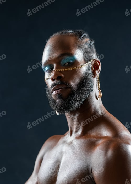 Preview: Confident bearded gay man with bright makeup in black studio