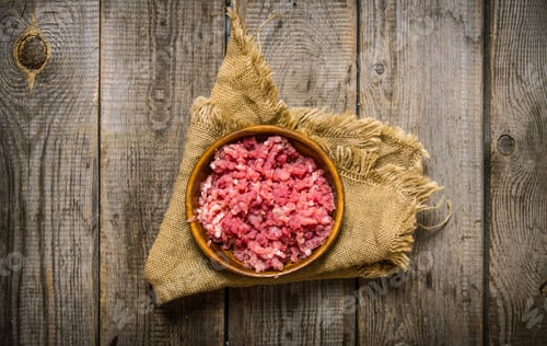 Preview: Raw minced meat in a wooden bowl on old fabric.