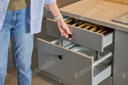 Preview: Person opening kitchen drawer with cutlery in cabinet