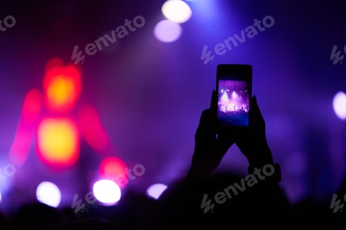 Preview: Hand with phone records live music festival. People taking photographs with phone during concert.