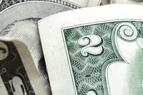 Preview: Close up view of two dollar bills stacked together on a plain surface