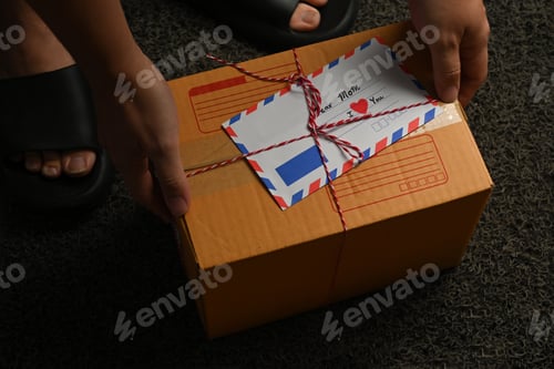 Preview: Man receiving deliver parcels box with greeting card on the door mat.
