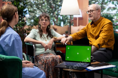 Preview: Caregiver consulting elderly woman in wheelchair next to green screen