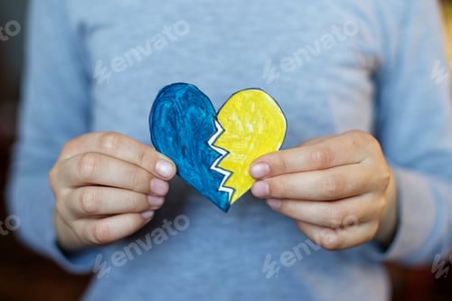 Preview: Heart of yellow-blue colors of national flag of Ukraine in childs hand. Top view. Stop War.