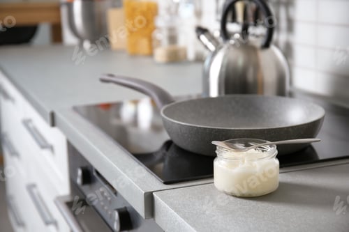Preview: Jar with coconut oil on table near kitchen stove