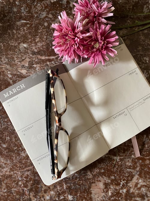 Preview: Daily planner on desktop with eyeglasses and pink flowers