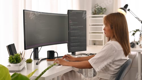 Preview: Side view of concentrated young woman software developer working with coded data.